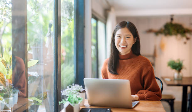 Happy young Asian girl working at a coffee shop with a laptop student